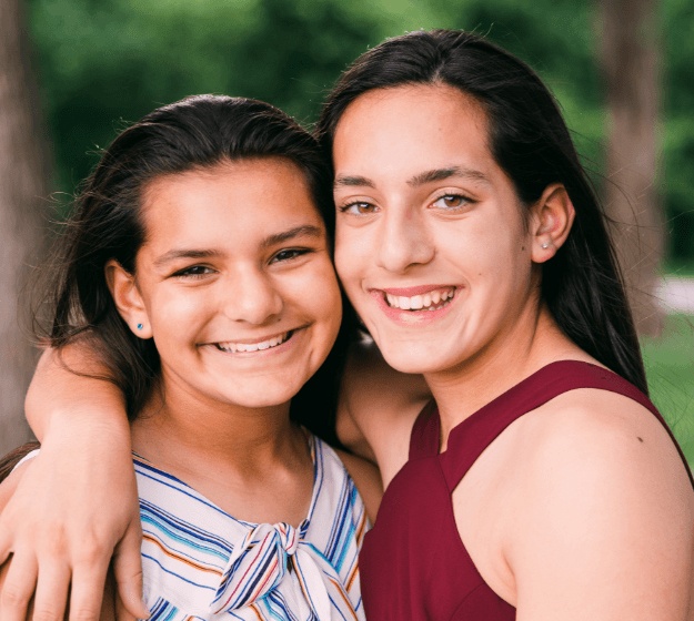 Two teens smiling after receiving dentofacial orthopedics