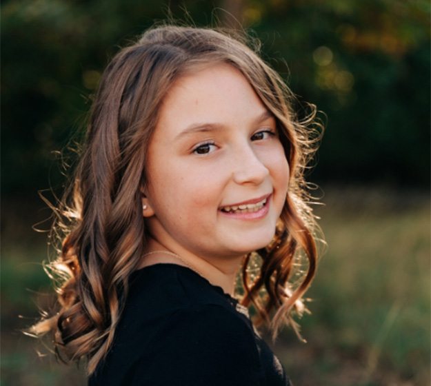 A young woman smiling and showing off her braces in Richardson