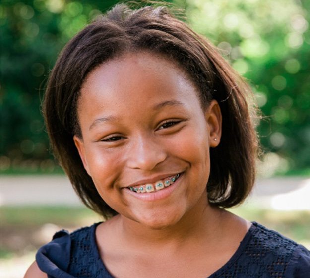 A young female wearing braces and having her orthodontist in Richardson review her smile