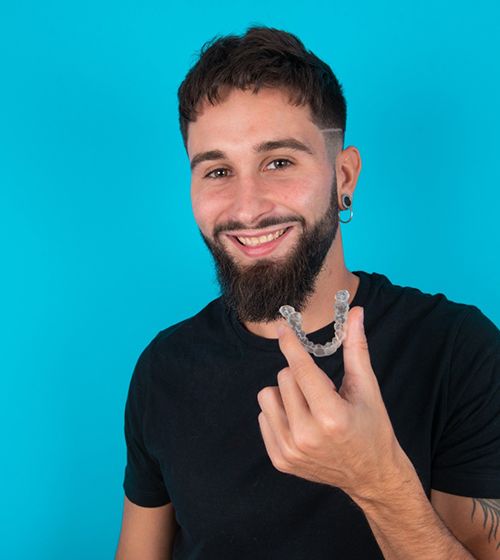 Smiling young man holding clear aligner