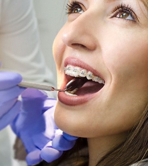 A woman’s orthodontist examines her smile during an appointment in Richardson