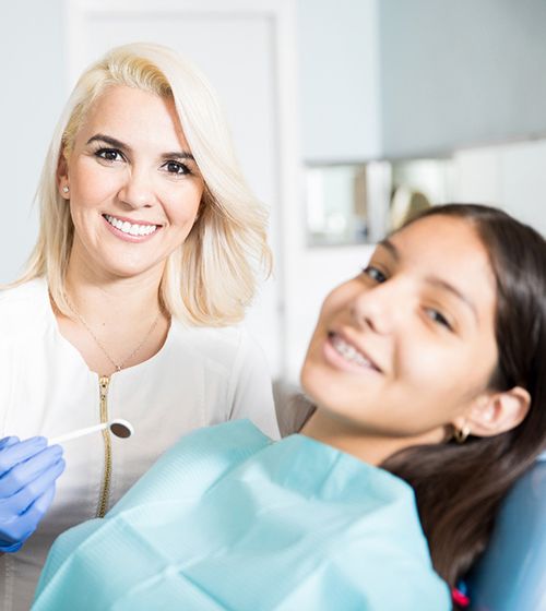 A female orthodontist preparing to perform orthodontic work on a teenage girl