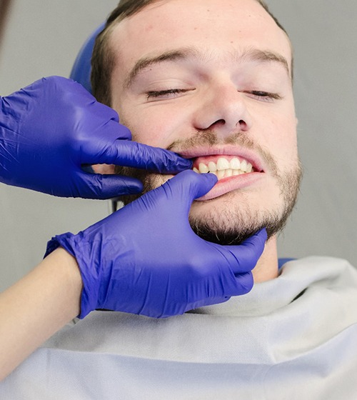 An orthodontist looking a young man’s smile to determine if he needs braces