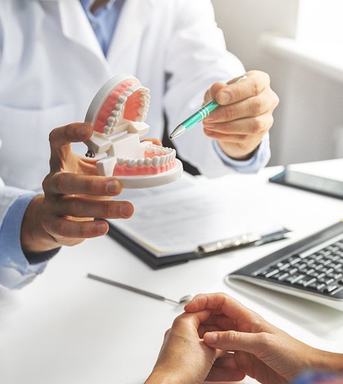 A dental professional using a mouth mold to show a patient how their teeth should look with the help of braces