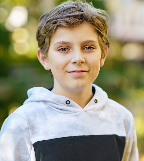 Preteen boy, standing outside and smiling