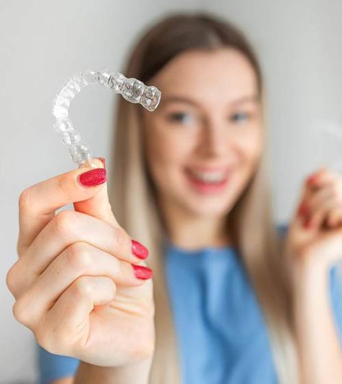 Woman holding two Invisalign aligners