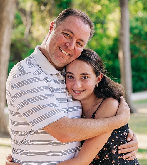 Young girl with braces giving her father a hug