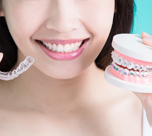woman holding Invisalign and braces