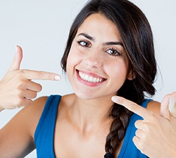young woman pointing to smile 