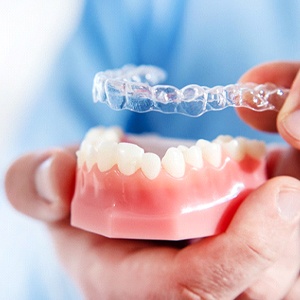 A dentist holding a mouth mold and preparing to place an Invisalign aligner over the bottom arch in Richardson