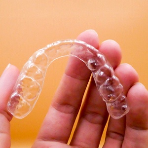 A person holding an Invisalign aligner in their hand in Richardson