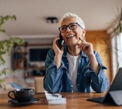 Woman with black glasses smiling while talking on phone