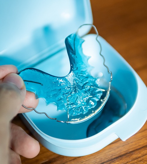 Patient placing blue retainer in blue storage case