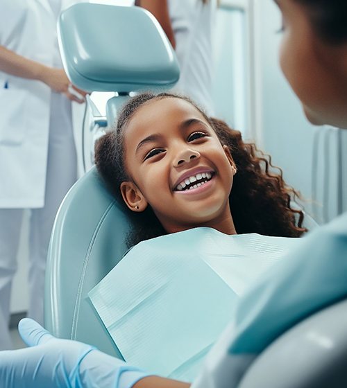 Child smiling while sitting in treatment chair