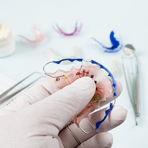 Hand in latex glove holding orthodontic appliance