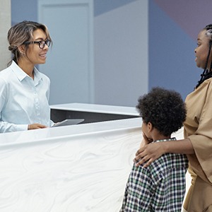 Mother and son using talking to orthodontic office employee