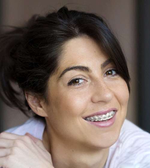 A woman smiling and showing off her top row of braces