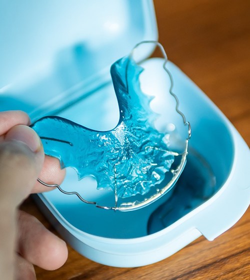 Person holding oral appliance for orthodontic retention