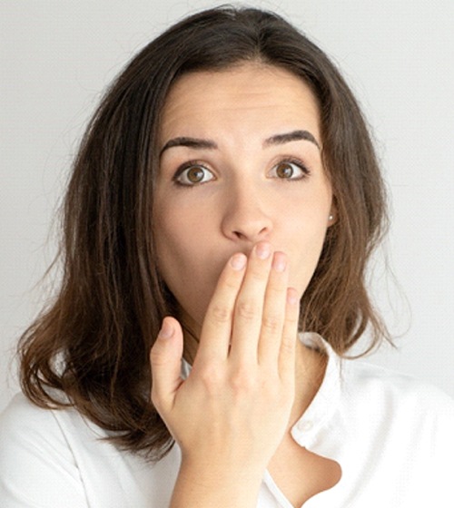 Brunette woman covering mouth, embarrassed by misaligned teeth