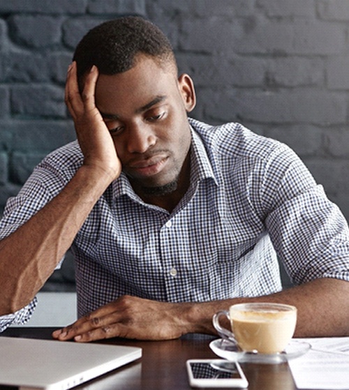 Tired man at desk, needs orthodontic treatment to address OSA