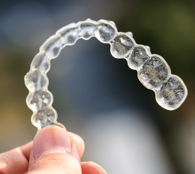 Hand holding an Invisalign alignment tray