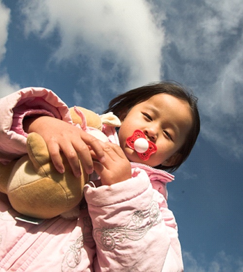 young child holding a stuffed animal and sucking on a pacifier