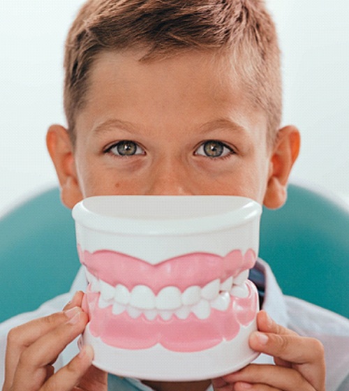 a child holding a model of a mouth up to their face