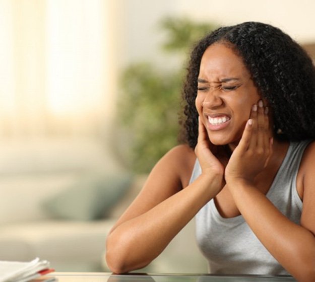 a woman experiencing pain due to T M J disorder