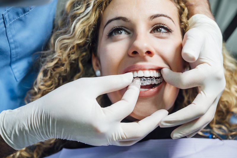 Closeup of orthodontist putting Invisalign tray on patient's top teeth