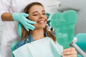 Patient looking at her teeth in mirror after braces removal