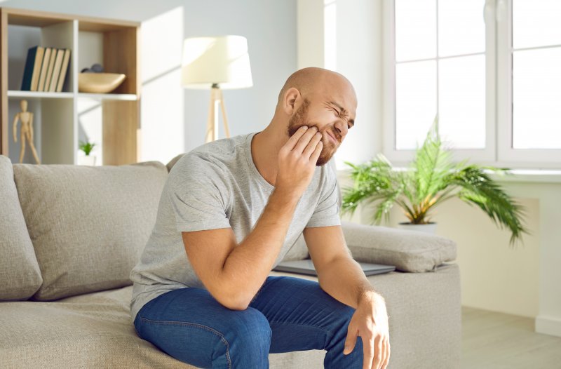 Man with TMJ disorder holding his jaw