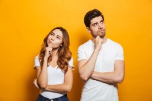 Two young adults wearing thoughtful, curious expressions