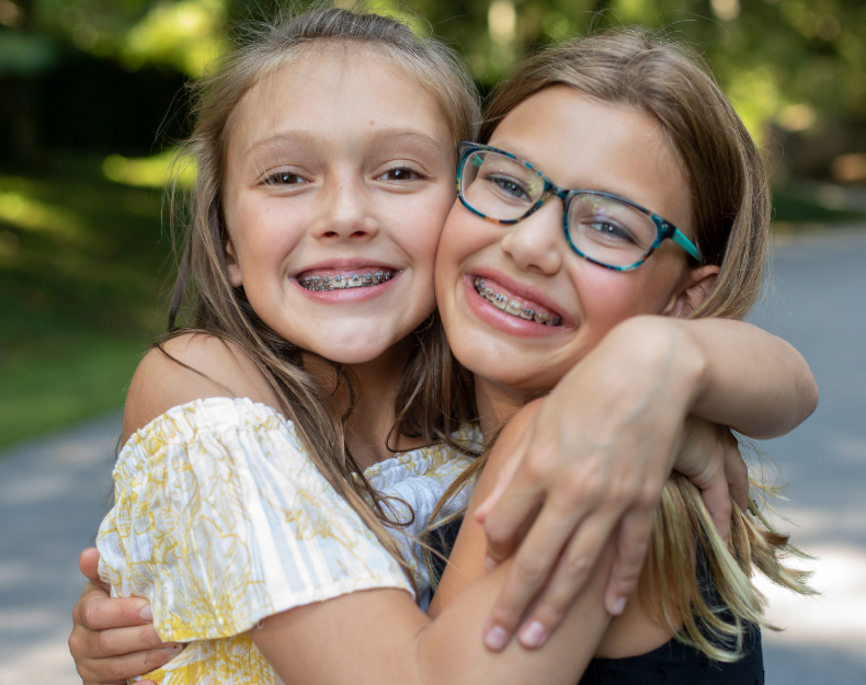 Girls hugging and smiling with braces