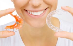 Woman holding retainer and clear aligner. 